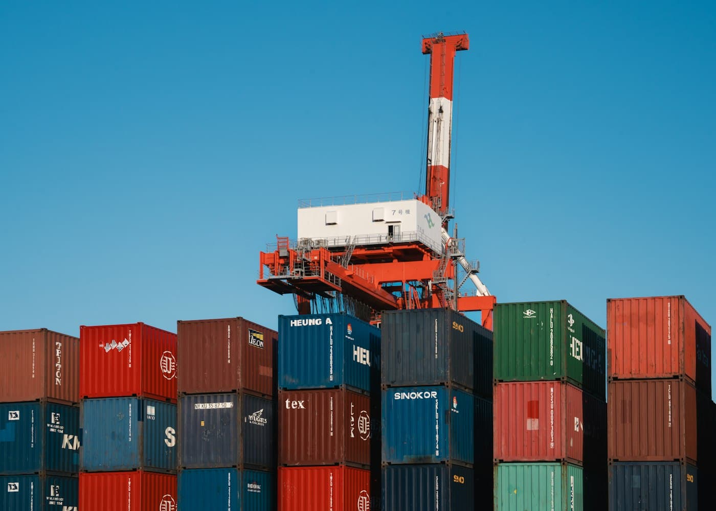 Stacks of shipping containers and a gantry crane at a cargo terminal